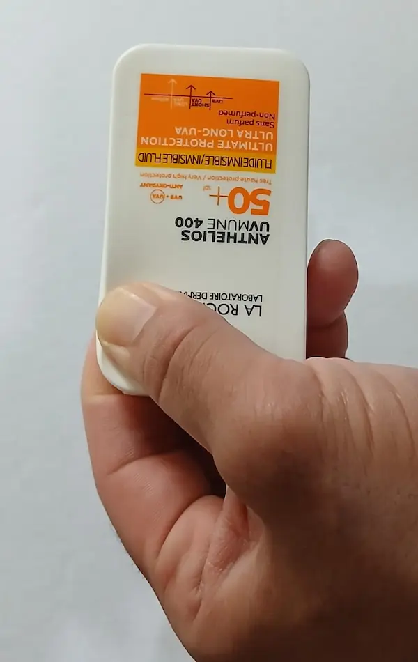 Fake La Roche-Posay Anthelios sunscreen bottle being pressed at the top corner with one thumb, the hard stiff plastic does not move outward